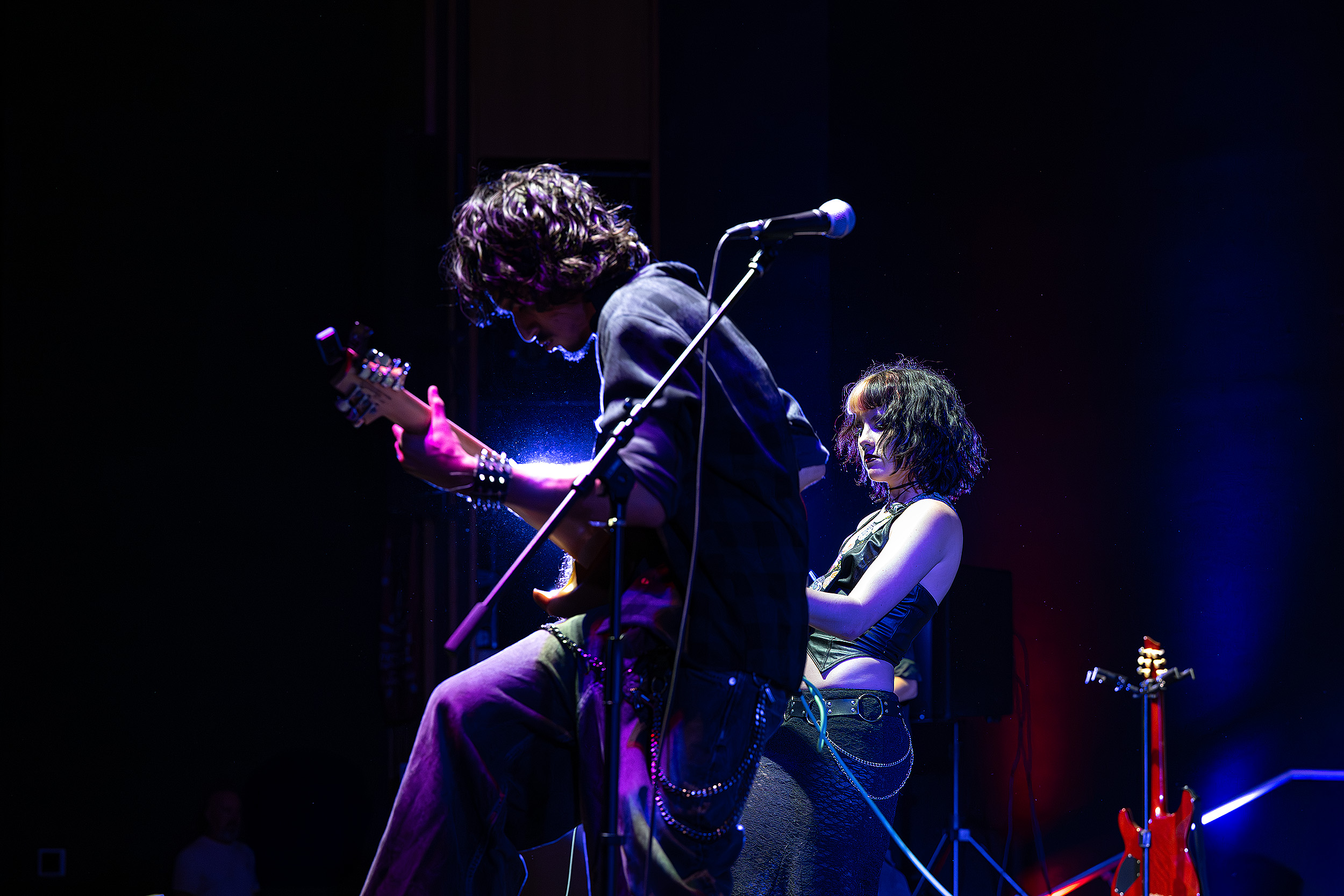 Musicians performing under dramatic blue and purple stage lights